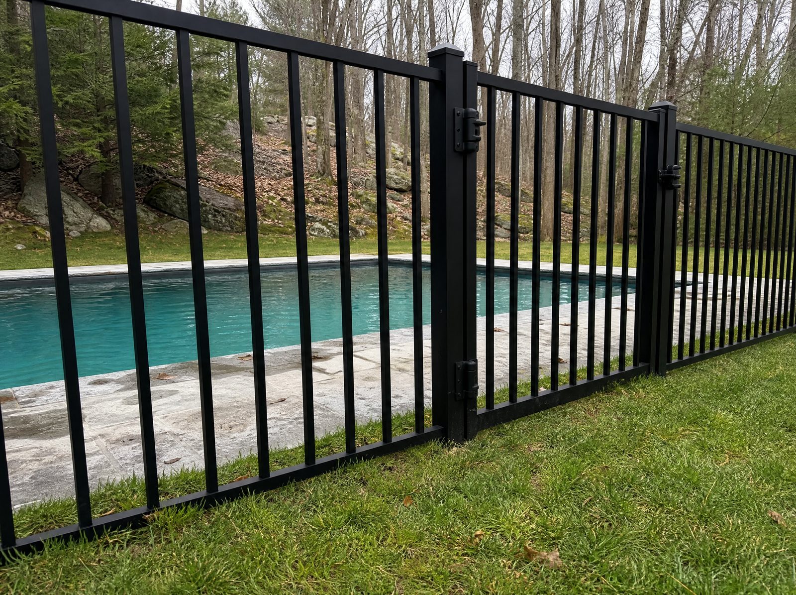 Four foot black aluminum pool fence with a self-closing gate enclosing a backyard swimming pool