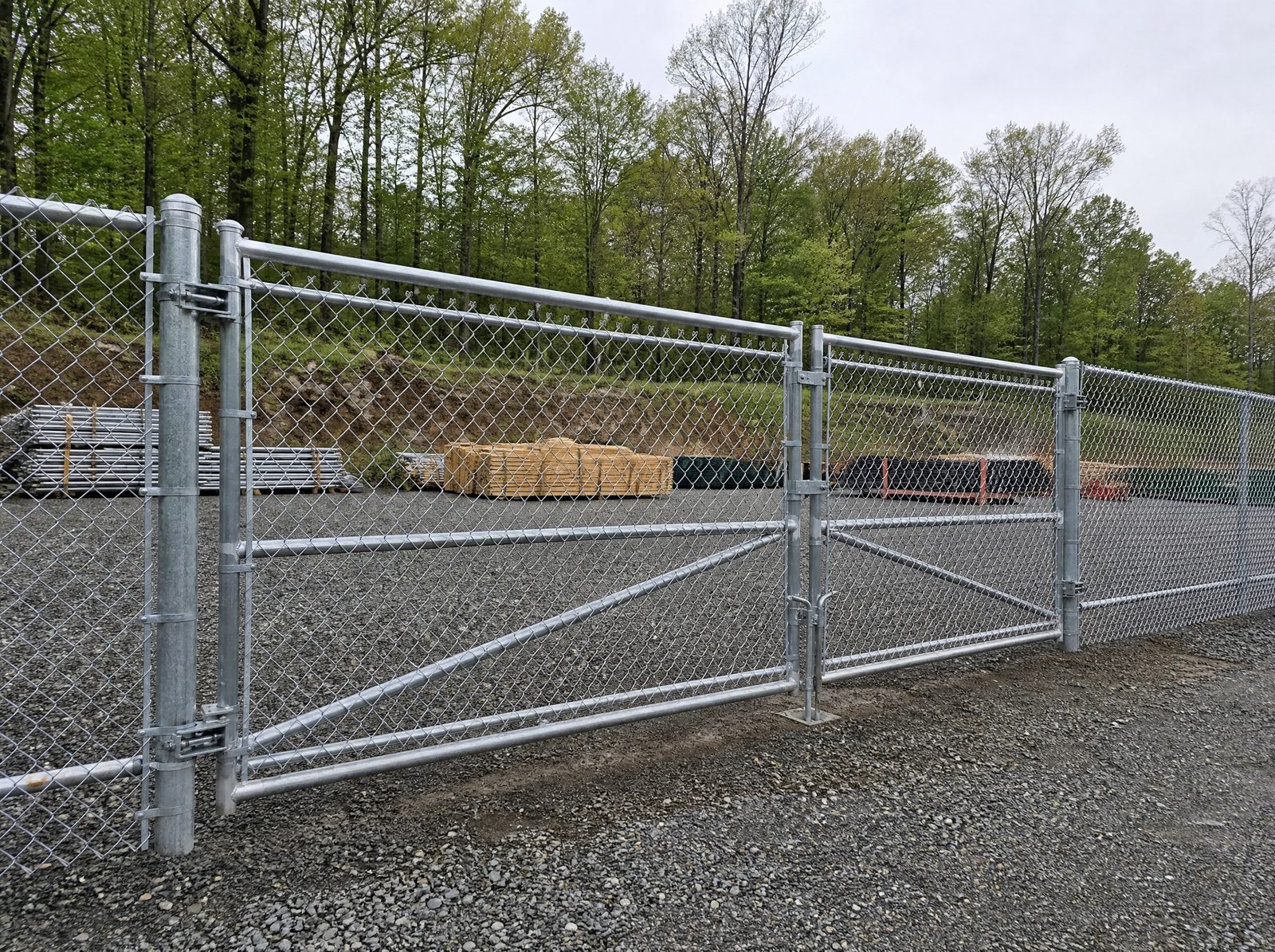 Six foot galvanized chain-link fence with a reinforced vehicle gate securing a service and equipment yard at a rural Sherman business property