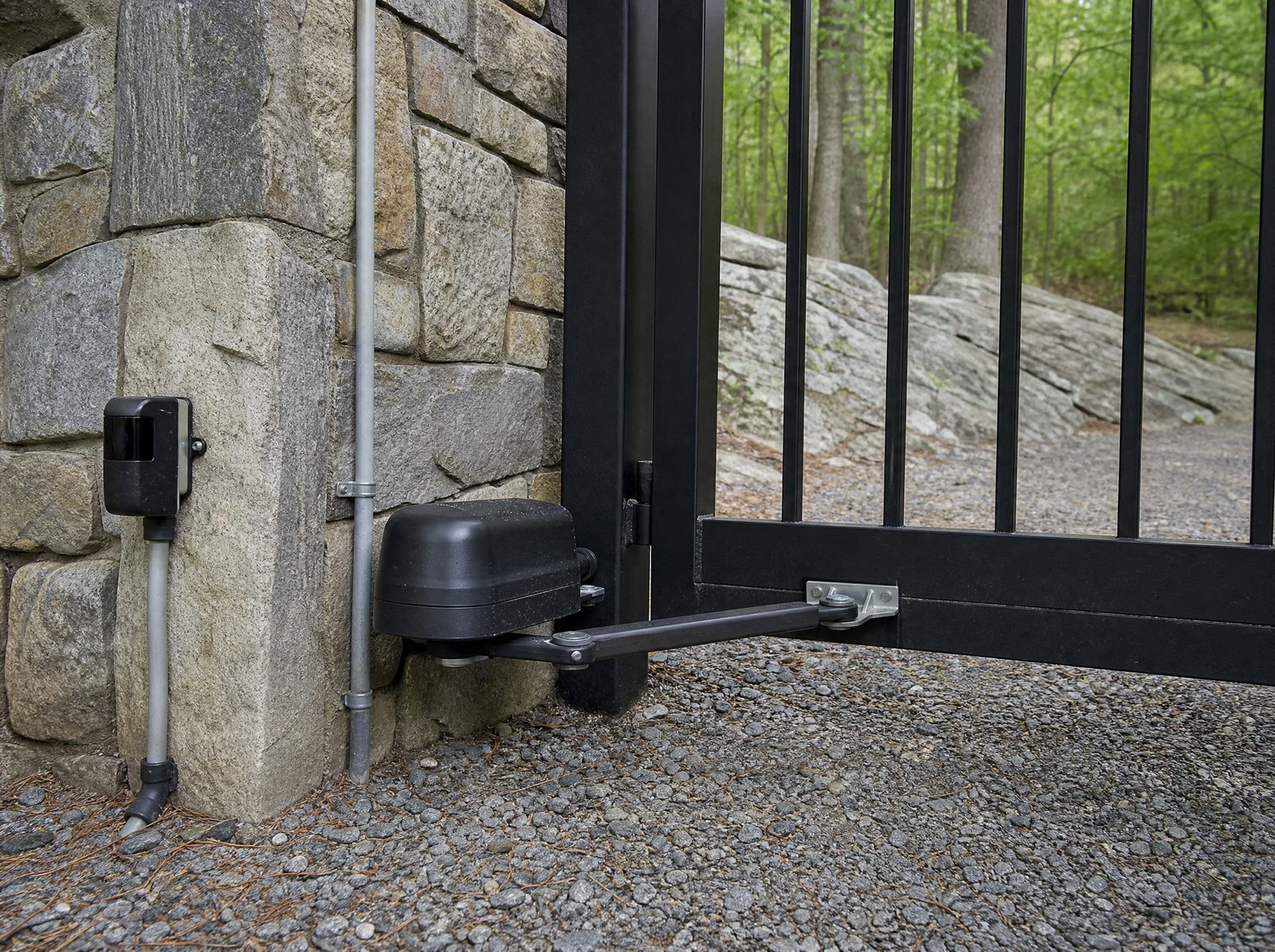 Swing gate operator and a low mounted photo-eye safety sensor mounted at the masonry column of a closed black estate gate
