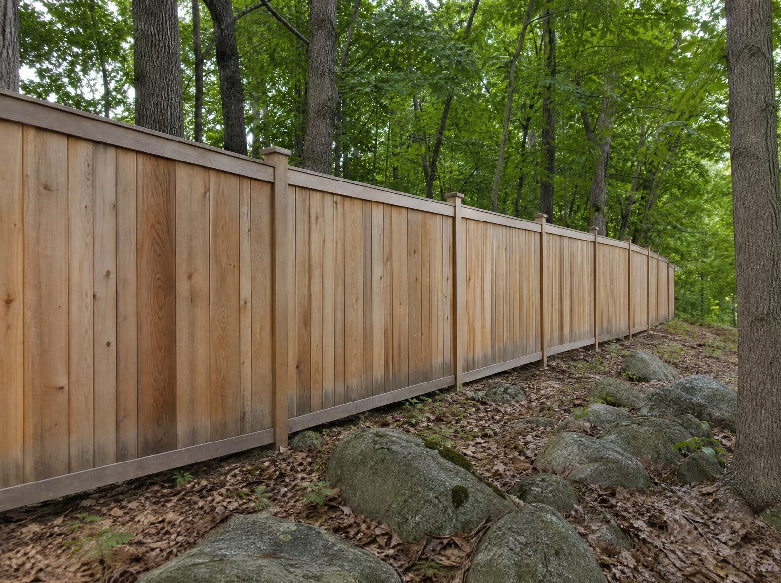 Six foot cedar board-on-board privacy fence holding a straight line along a wooded rural property boundary over uneven ground