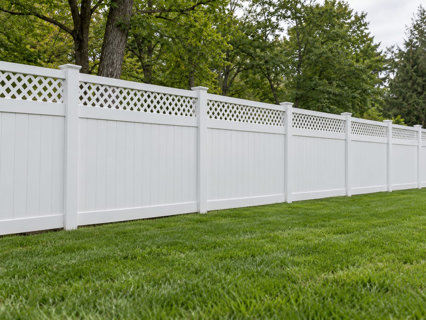 A white vinyl privacy fence with an open lattice top along a level backyard lawn in western Connecticut.