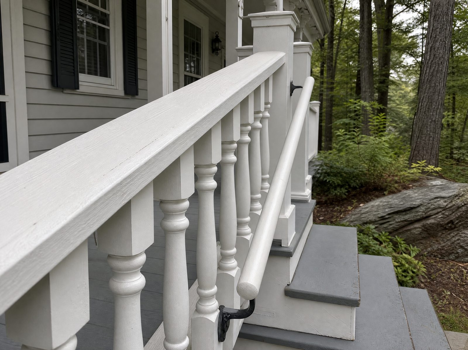 Wide flat wood cap rail on a porch guard beside a separate round graspable wood handrail mounted on brackets along the steps