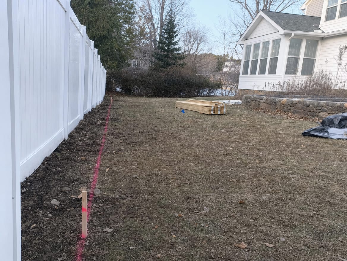A backyard prepared for new fence construction with a marked and cleared property line