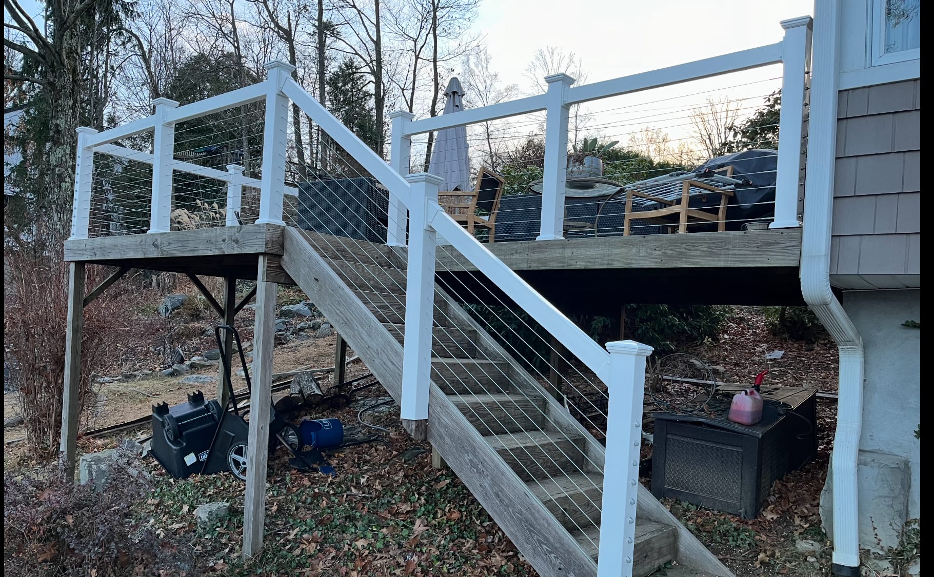 White vinyl posts with horizontal stainless cable railing on an elevated wood deck and staircase