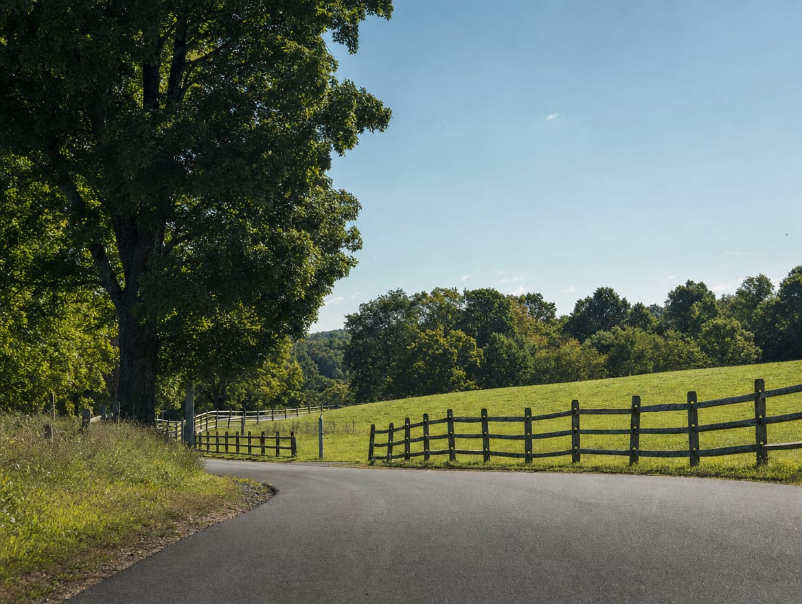 A rural Connecticut road winding past fields bordered by wood post and rail fencing