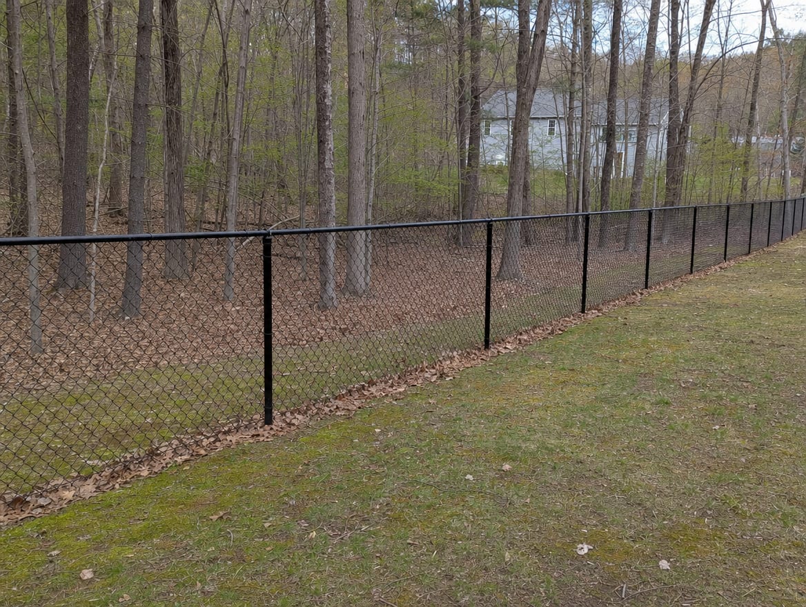 A black chain link fence running along a rear property line of a backyard in Bethel, CT