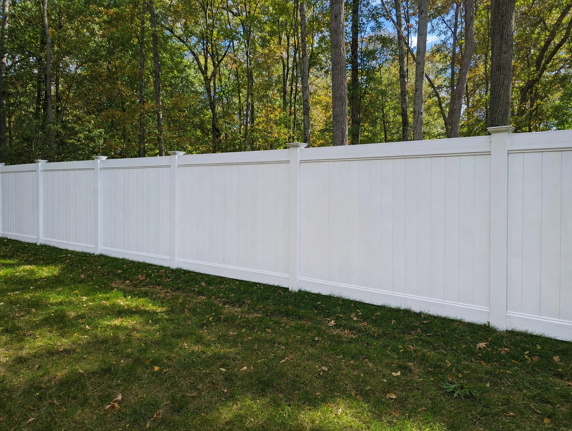 A full six foot tall white vinyl privacy fence running along a backyard property line in Brewster, NY