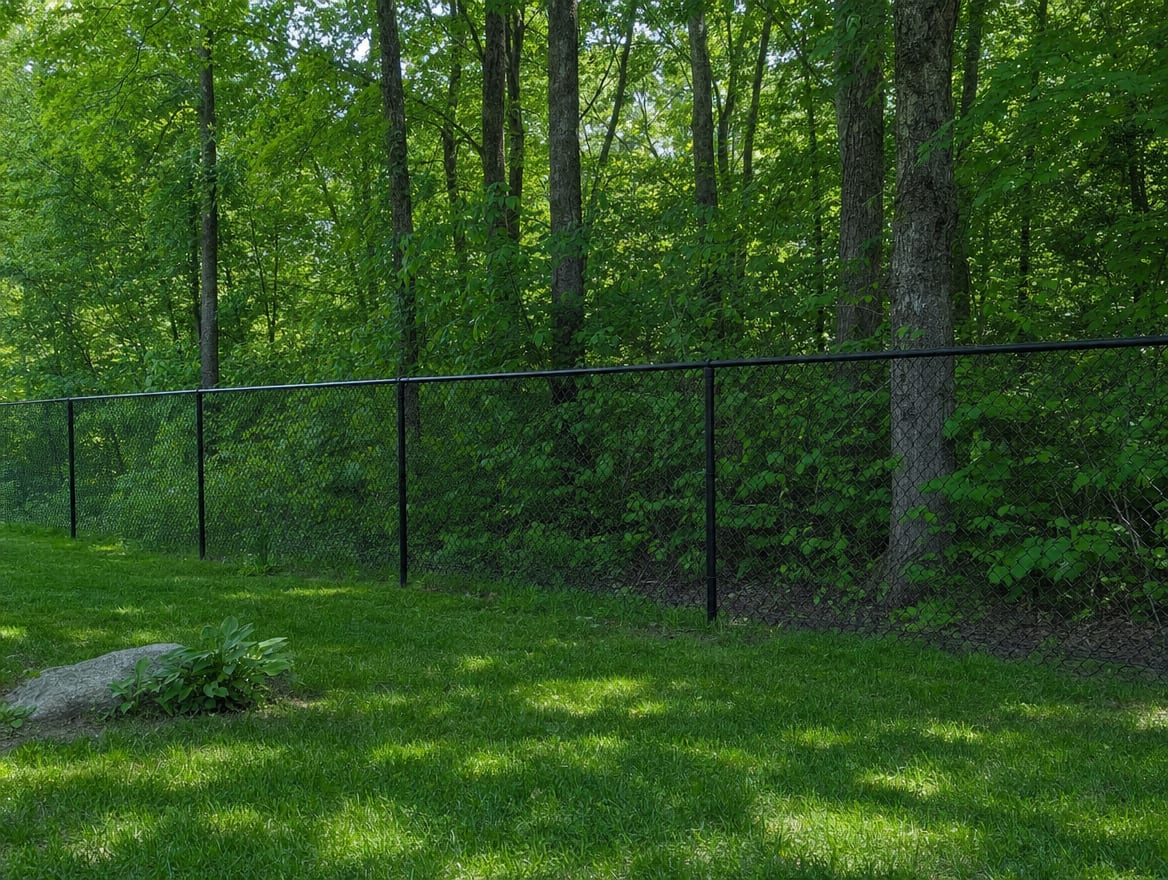A black chain link fence running along a rear property line of a backyard in Brookfield, CT