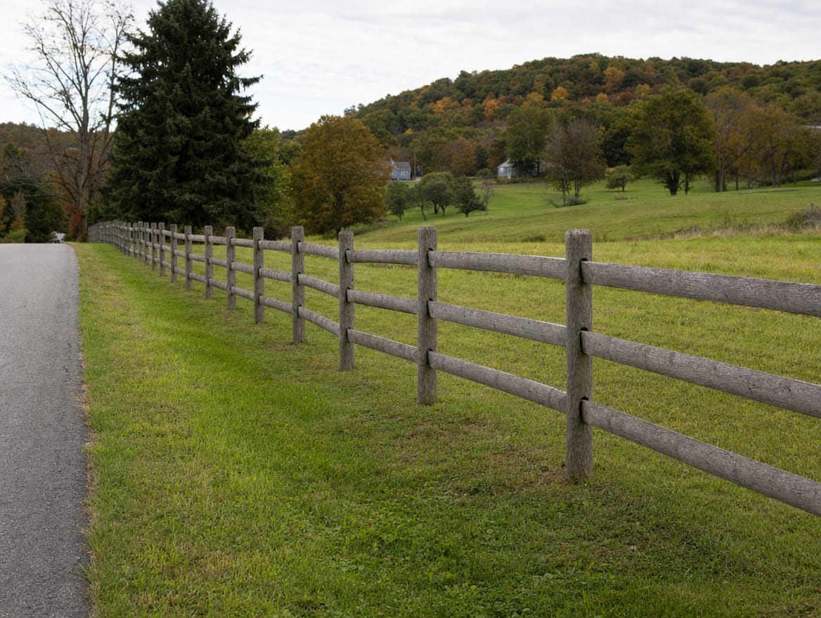 A wood split-rail or post-and-rail fence running along the edge of a field in Canaan, CT