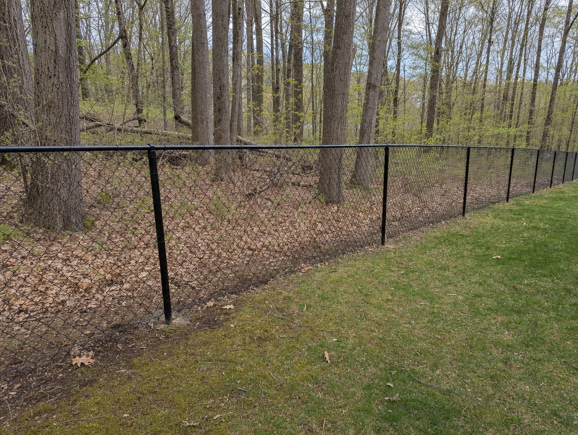 A black chain link fence running along a rear property line of a backyard in Meriden, CT