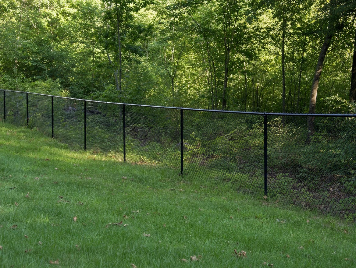 A black chain link fence running along a rear property line of a backyard in New Fairfield, CT
