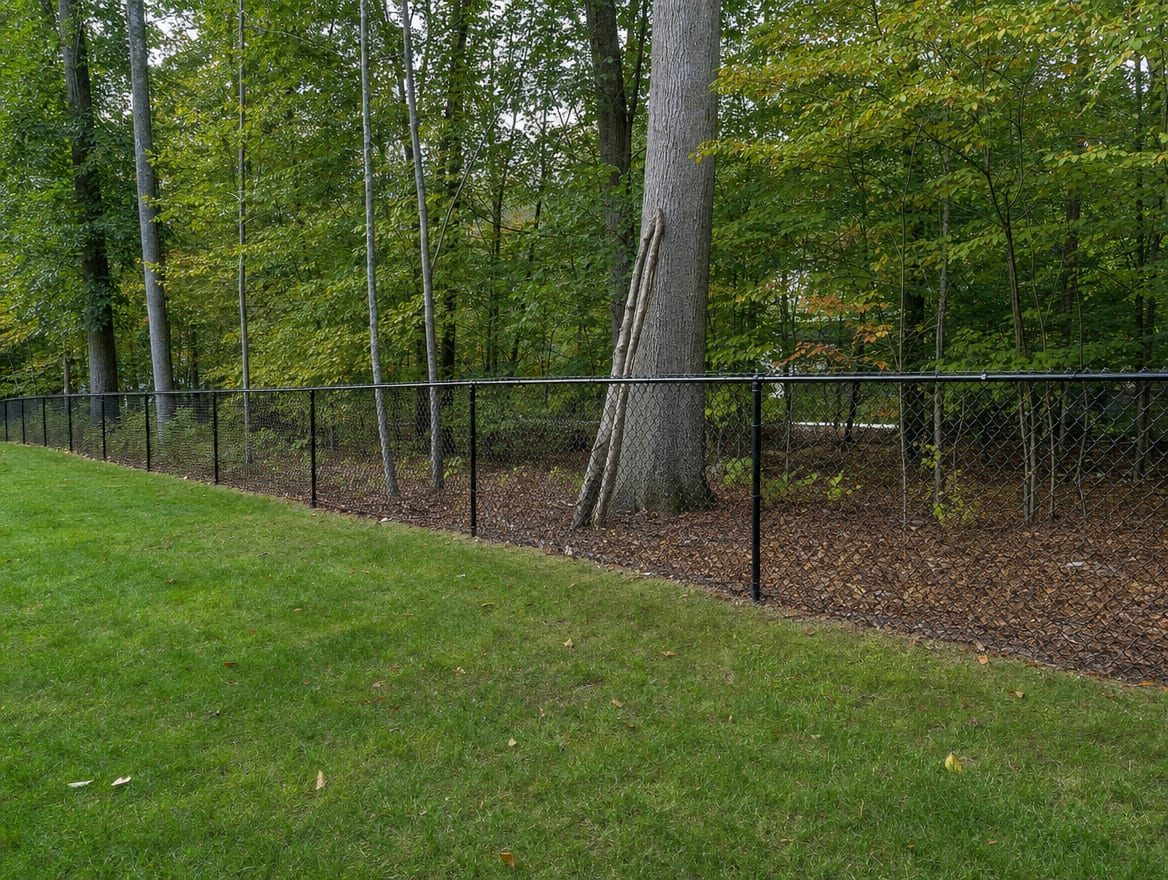 A black chain link fence running along a rear property line of a backyard in Newtown, CT