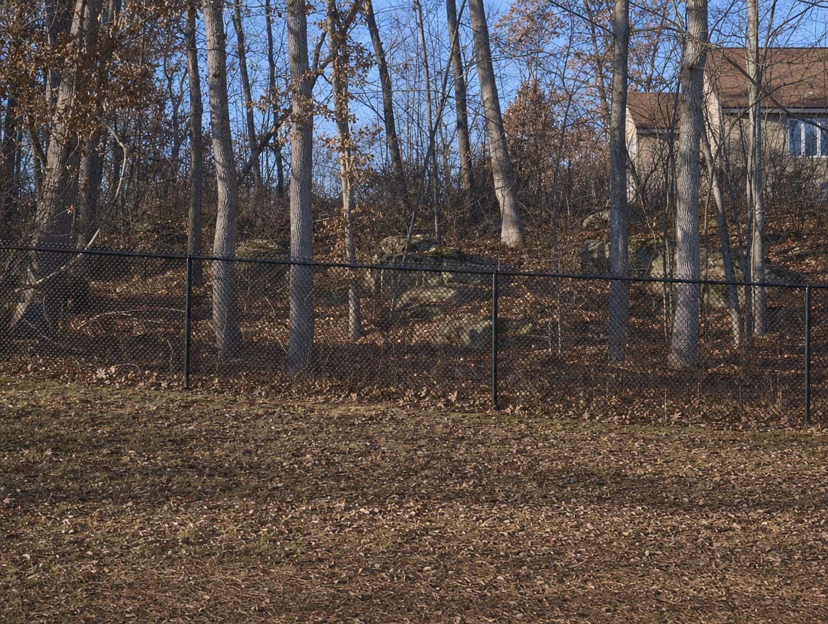 A black chain link fence running along a rear property line of a backyard in Pawling, NY