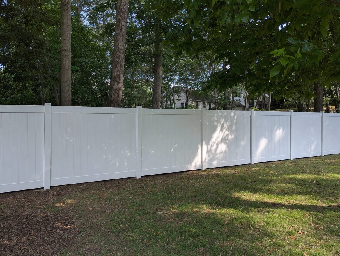 A full six foot tall white vinyl privacy fence running along a backyard property line in Prospect, CT