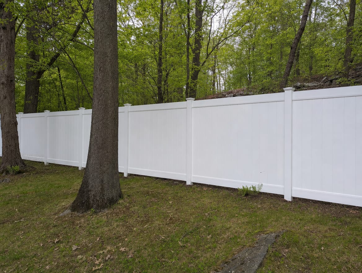 A full six foot tall white vinyl privacy fence running along a backyard property line in Ridgefield, CT