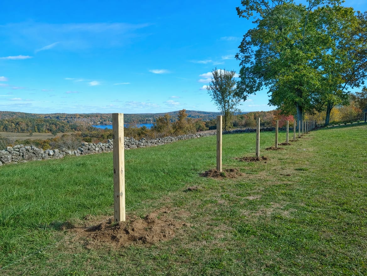 A fence installation in progress with newly set posts in Warren, CT