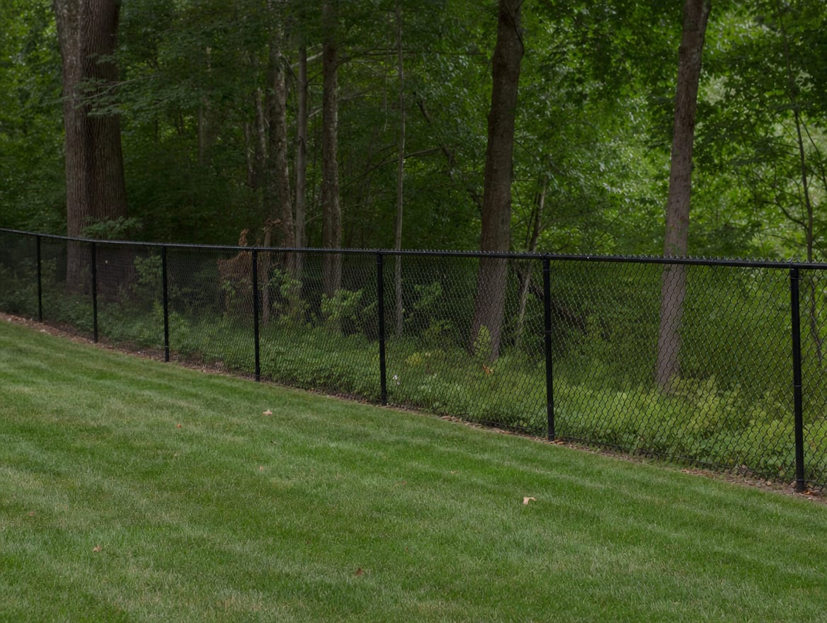 A black chain link fence running along a rear property line of a backyard in Washington, CT