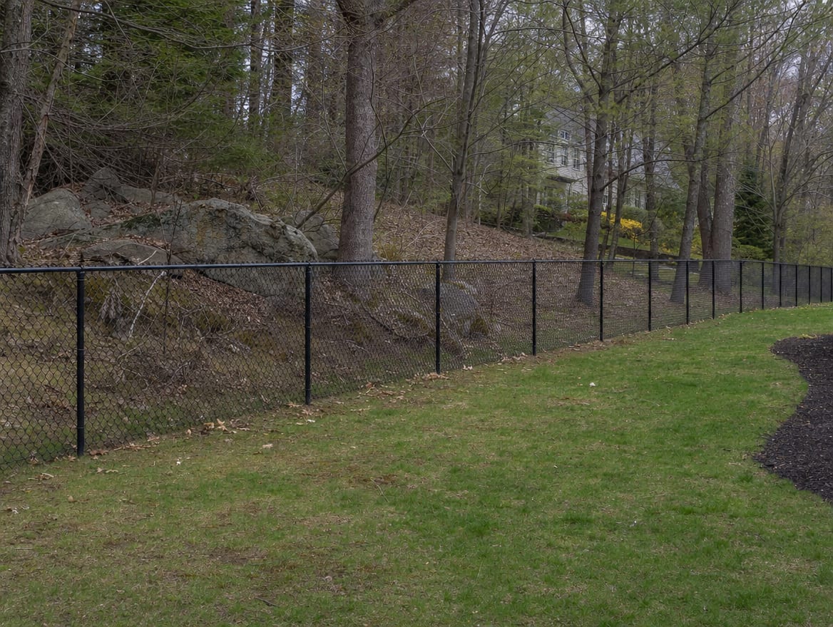 A black chain link fence running along a rear property line of a backyard in Weston, CT