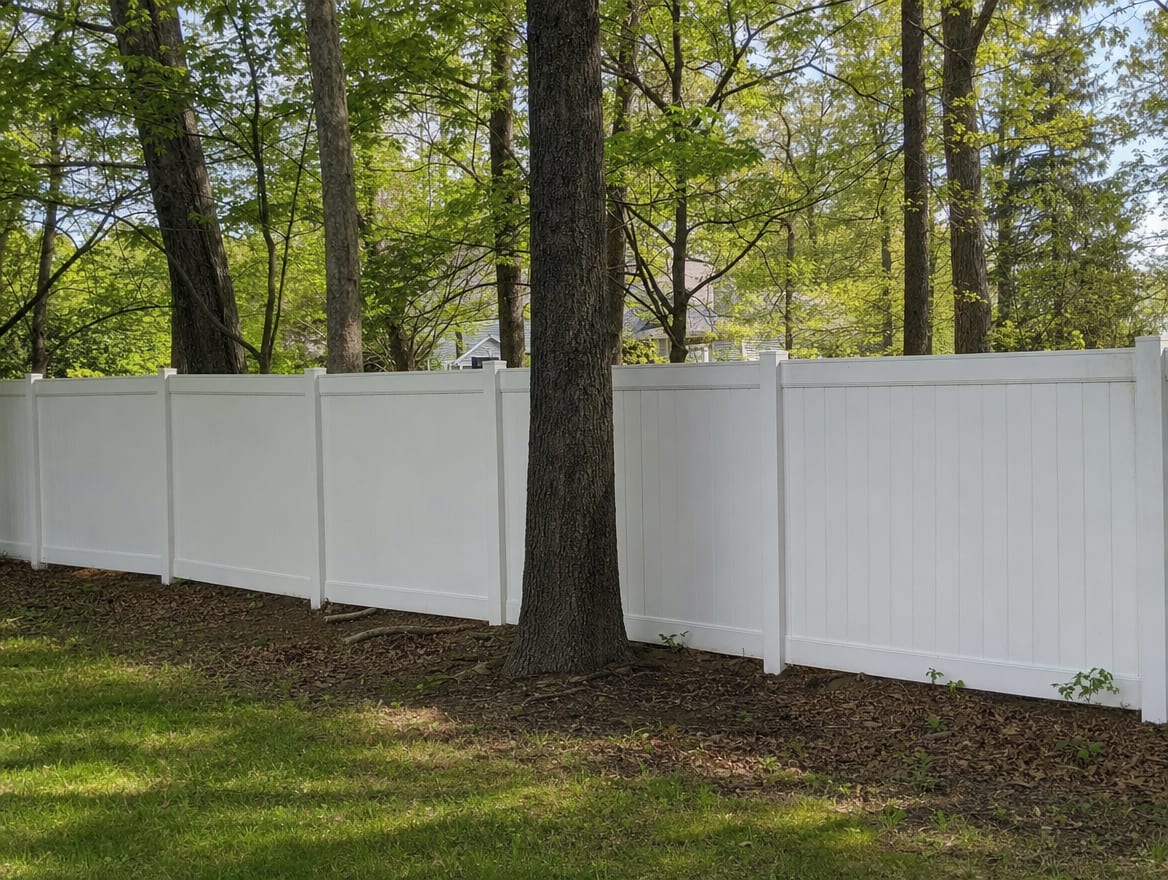 A full six foot tall white vinyl privacy fence running along a backyard property line in Woodbury, CT