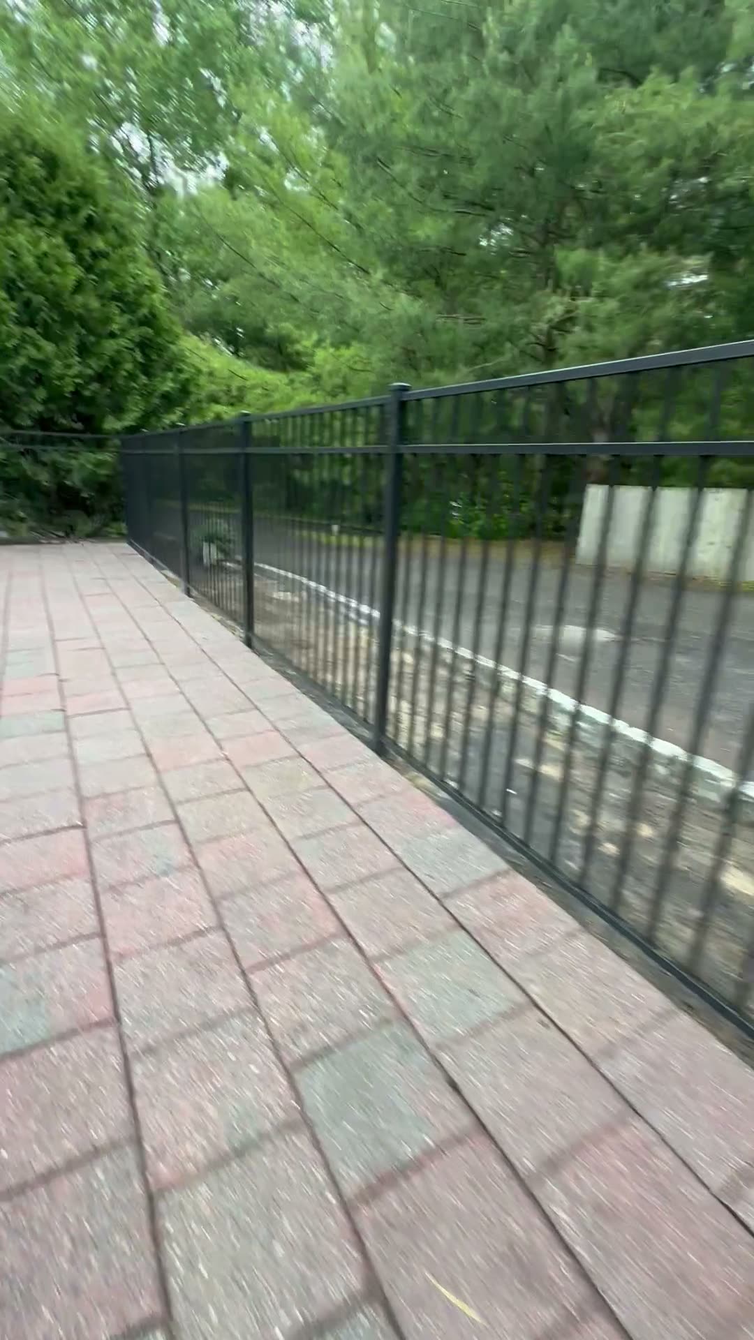 Black aluminum fence along a paver walkway