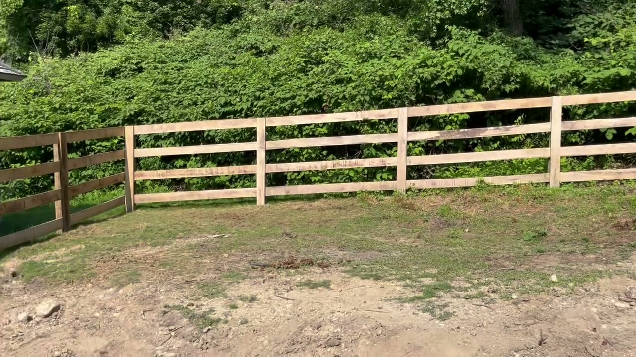 Wood four-rail double driveway gate at a property entrance