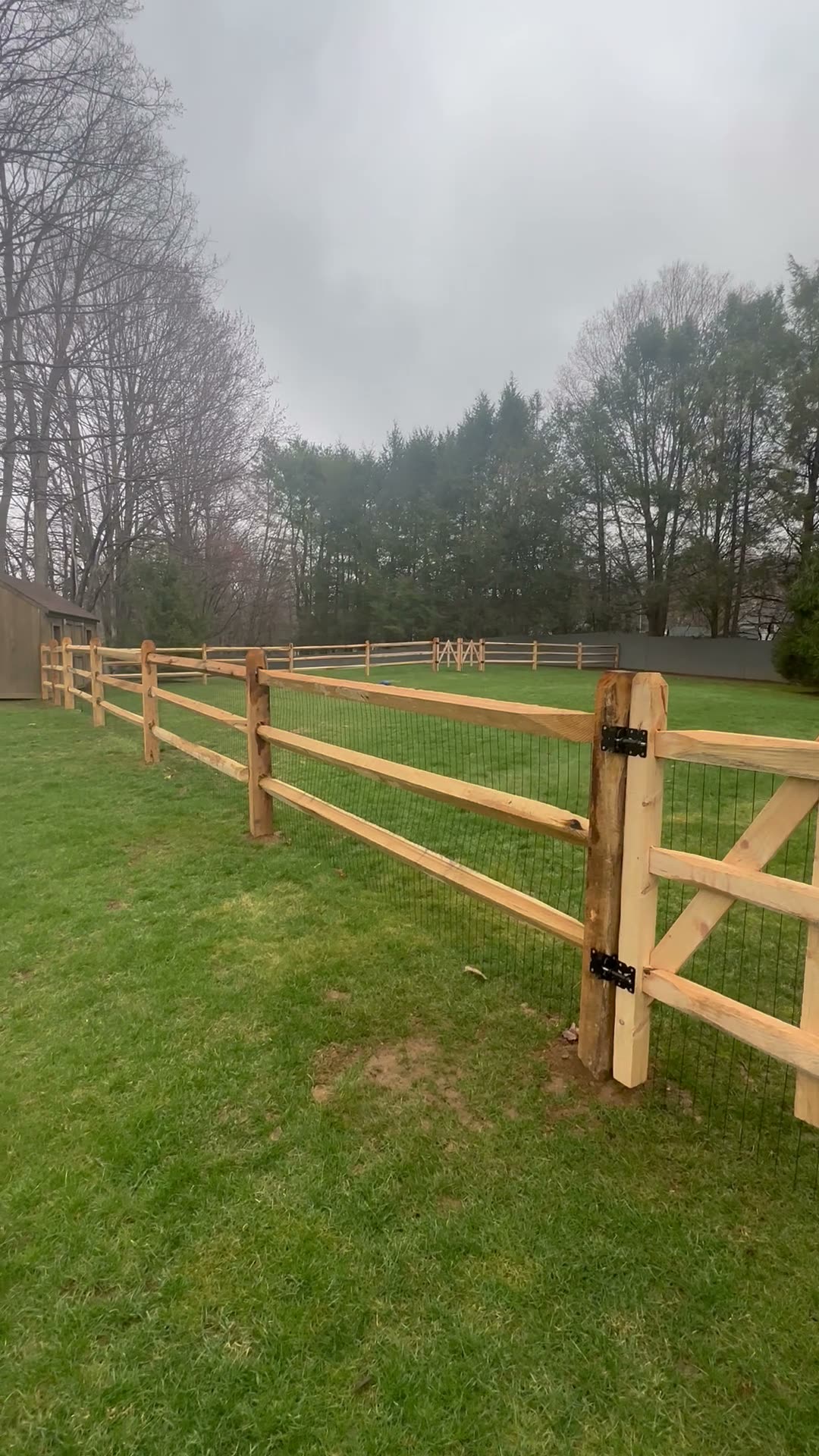 Cedar post-and-rail fence with wire mesh and a gate