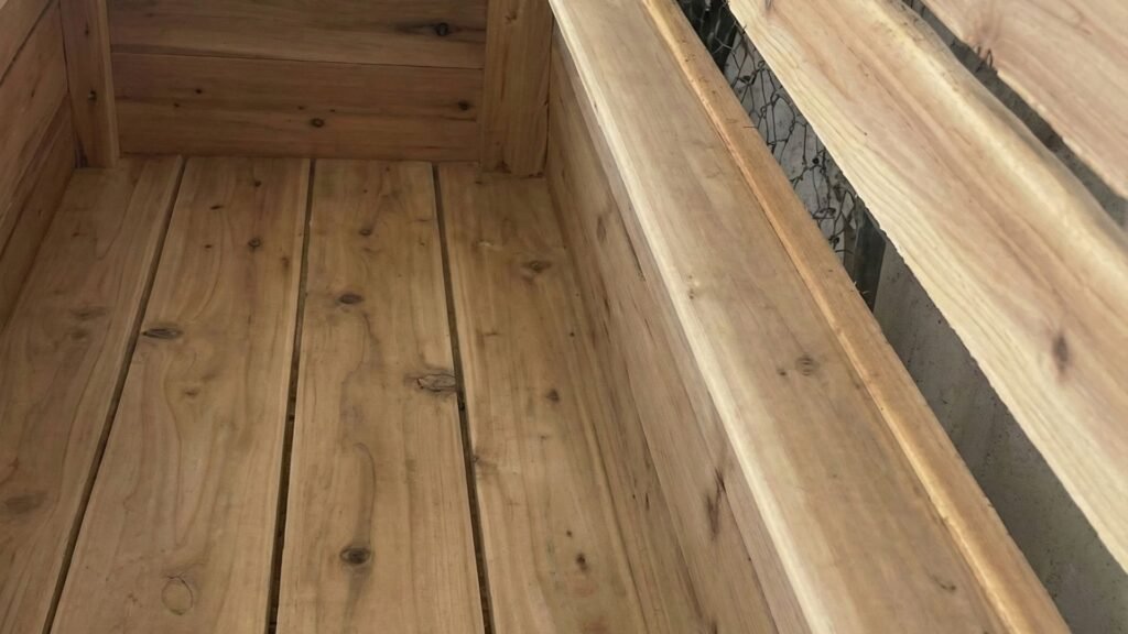 Unfinished cedar planter box with wooden slats and natural grain visible in workshop setting