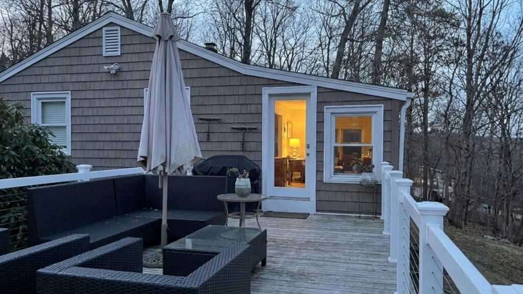 Modern deck with white cable railings and dark wicker furniture, showing professional railing installation on home exterior