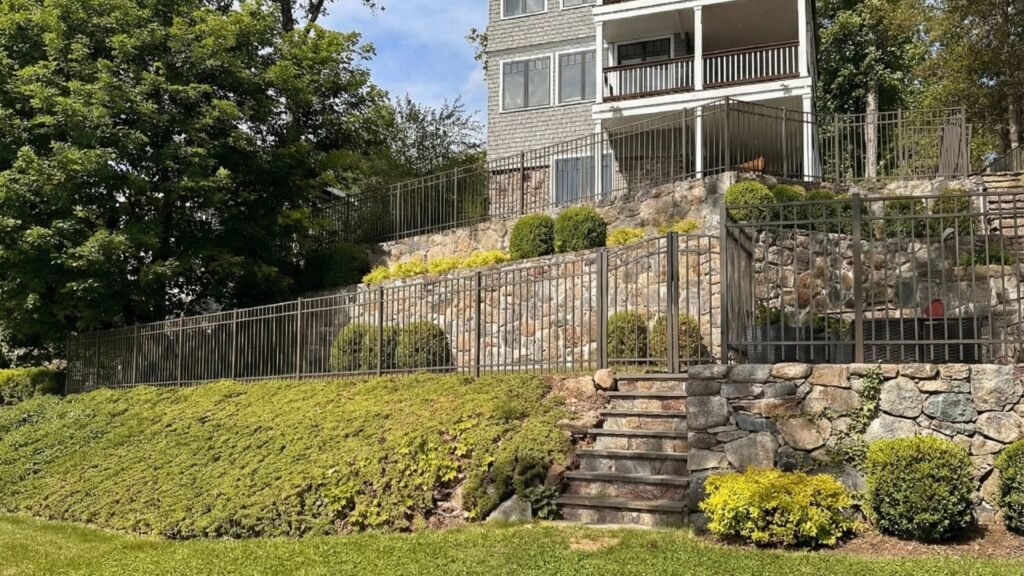 Sloped residential yard prepared for fence installation with clear access along the property line