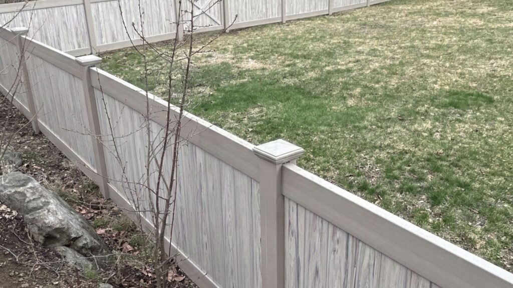 New vinyl privacy fence with horizontal slats and decorative posts installed in residential backyard