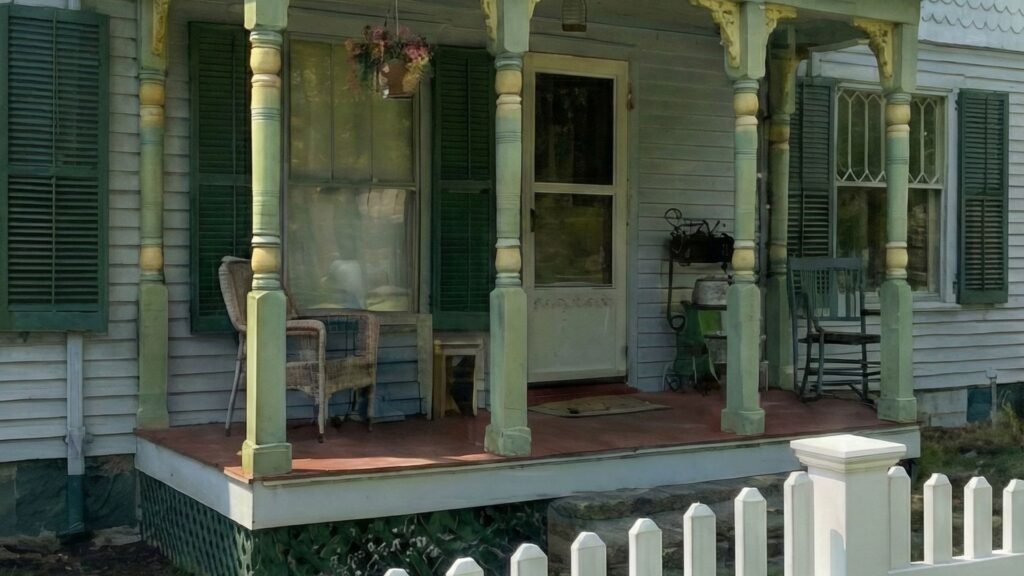 White picket fence in front of Victorian home with green shutters and covered porch in Amenia NY